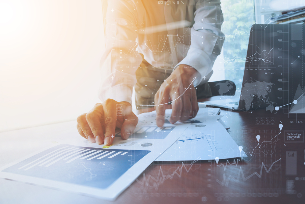 business documents on office table with smart phone and digital tablet and graph financial with social network diagram and man working in the background